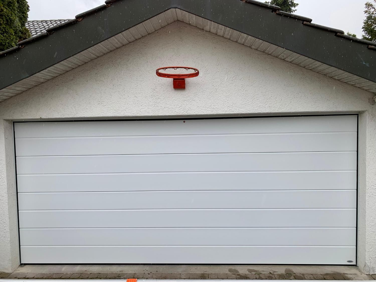 Weisses Sektionaltor an einer Garage mit Basketballkorb