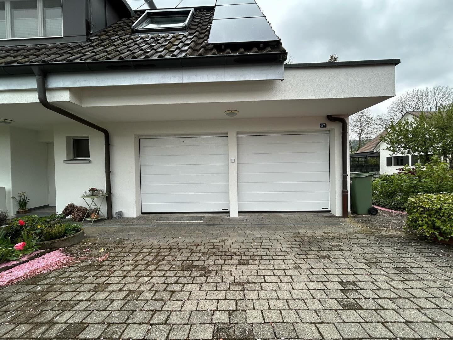 Zwei weisse Sektionaltore an einem Haus mit Solaranlage