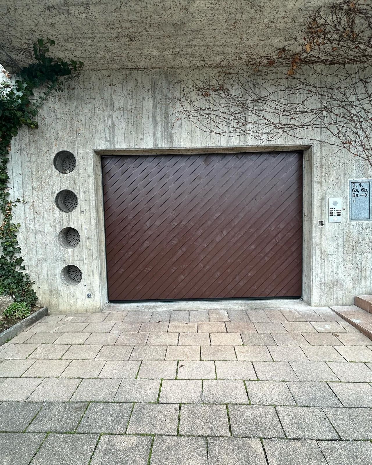 Braunes Tor mit Fischgrätmuster an einer Betonwand